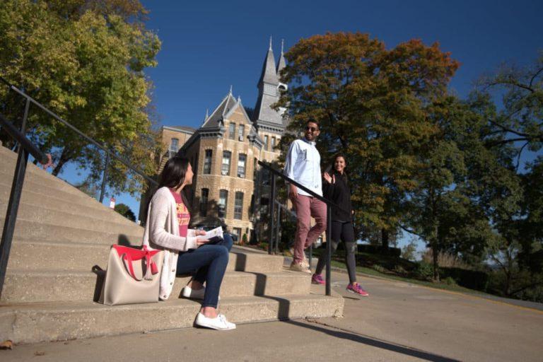 students on steps in front of campus building