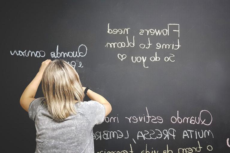 student writing on blackboard